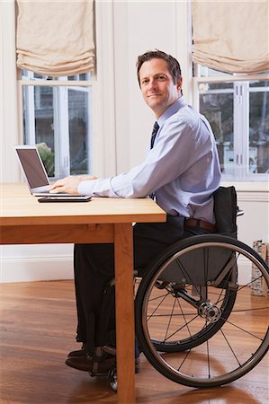 simsearch:6105-07744463,k - Businessman with spinal cord injury in a wheelchair working on laptop Photographie de stock - Premium Libres de Droits, Code: 6105-07521209