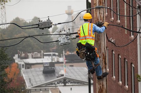 simsearch:6105-07521269,k - Cable lineman using lineman spikes to climb down pole Stock Photo - Premium Royalty-Free, Code: 6105-07521239