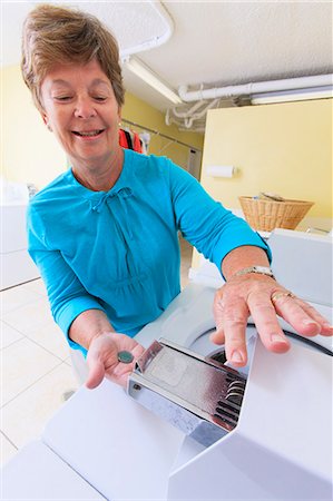 Senior woman putting money into a commercial washing machine Fotografie stock - Premium Royalty-Free, Codice: 6105-07521347