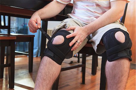 Man adjusting braces on his knees after anterior cruciate ligament (ACL) surgery Photographie de stock - Premium Libres de Droits, Code: 6105-07521361
