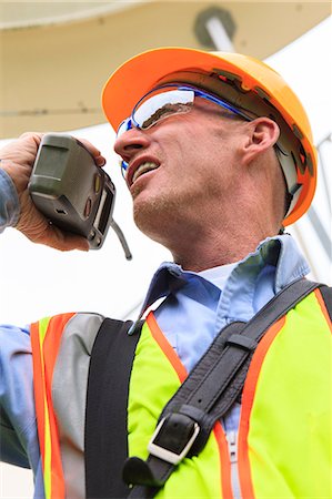 simsearch:6105-05953759,k - Engineer at electric power plant standing at satellite antenna dish while on walkie-talkie Stock Photo - Premium Royalty-Free, Code: 6105-07521480