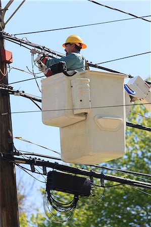 environment industry - Power engineer in lift bucket working on power lines, Braintree, Massachusetts, USA Stock Photo - Premium Royalty-Free, Code: 6105-07521407