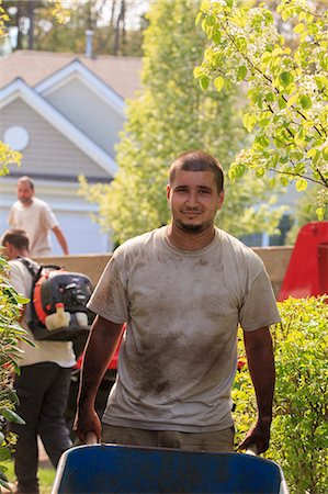 Landscaper carrying mulch to a garden in wheelbarrow Photographie de stock - Premium Libres de Droits, Code: 6105-07521422