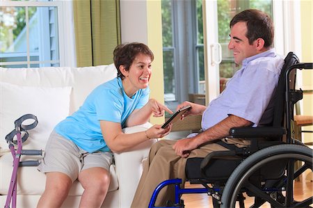 Couple with Cerebral Palsy looking at a digital tablet Stock Photo - Premium Royalty-Free, Code: 6105-07744361