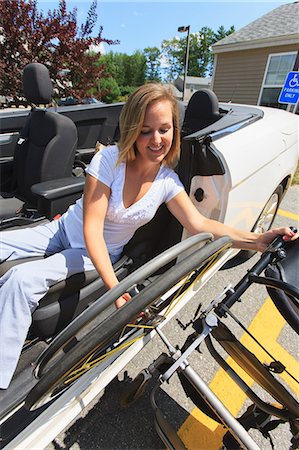simsearch:6105-07744367,k - Woman with spinal cord injury pulling wheel from wheelchair into her adaptive vehicle Foto de stock - Sin royalties Premium, Código: 6105-07744370