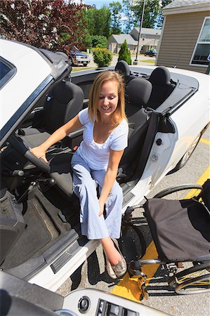 Woman with spinal cord injury lifting her leg to access her adaptive vehicle Stock Photo - Premium Royalty-Free, Code: 6105-07744371