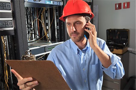 Network engineer on phone performing trouble shooting Stock Photo - Premium Royalty-Free, Code: 6105-07744484