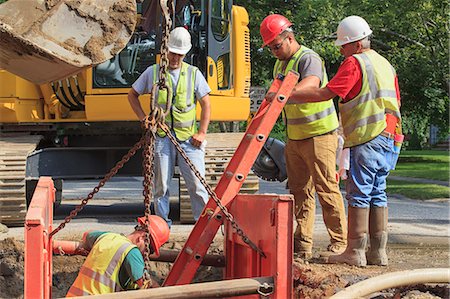 Construction workers preparing to climb down hole with ladder Stock Photo - Premium Royalty-Free, Code: 6105-08211248