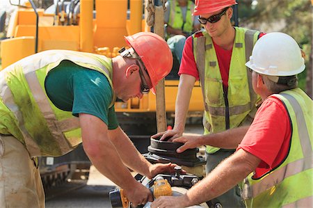 Construction workers using battery powered wrench to secure water main section with bolts Stock Photo - Premium Royalty-Free, Code: 6105-08211257