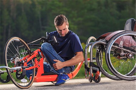 simsearch:6105-07744367,k - Man with spinal cord injury in his custom adaptive hand cycle getting into his wheelchair Foto de stock - Sin royalties Premium, Código: 6105-08211278