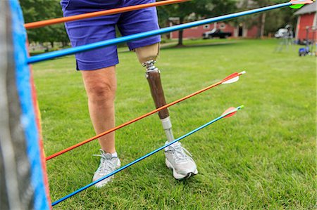 Woman with prosthetic leg pulling arrows from target after archery practice Photographie de stock - Premium Libres de Droits, Code: 6105-08211292