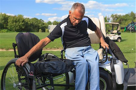 simsearch:6105-08211342,k - Man with a spinal cord injury in an adaptive golf cart getting into his wheelchair Photographie de stock - Premium Libres de Droits, Code: 6105-08211347