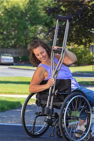 simsearch:6105-08211353,k - Woman with Spina Bifida attaching crutches to wheelchair Fotografie stock - Premium Royalty-Free, Codice: 6105-08211300