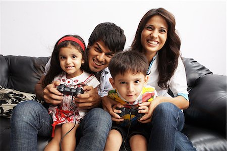 Portrait of parents sitting with their kids and playing video game Foto de stock - Sin royalties Premium, Código: 6107-06117605