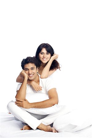 Portrait of a happy couple sitting on bed Stock Photo - Premium Royalty-Free, Code: 6107-06117913