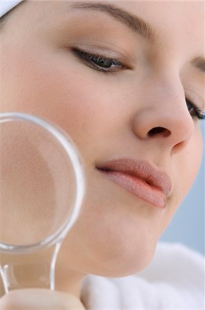 Young Woman with a magnifying glass, close-up (studio) Stock Photo - Premium Royalty-Free, Code: 6108-05855661