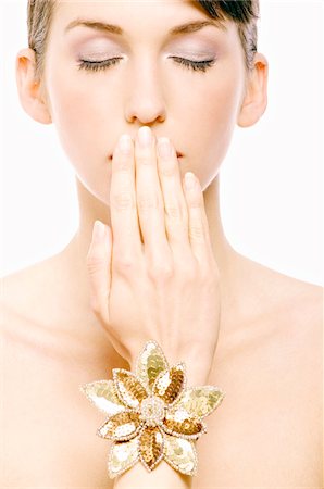 Visage de la jeune femme avec composent, ayant sa main devant sa bouche, close-up (studio) Photographie de stock - Premium Libres de Droits, Code: 6108-05855625