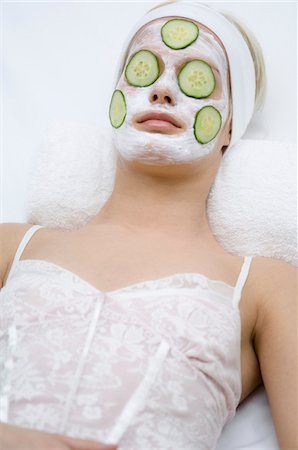 Portrait of a young woman with beauty mask on her face and slices cucumber on her eyes Stock Photo - Premium Royalty-Free, Code: 6108-05855756