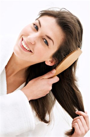 Portrait of a young woman brushing her hair Stock Photo - Premium Royalty-Free, Code: 6108-05855769