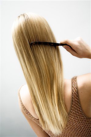 Young woman combing her hair, view from the back Stock Photo - Premium Royalty-Free, Code: 6108-05855770