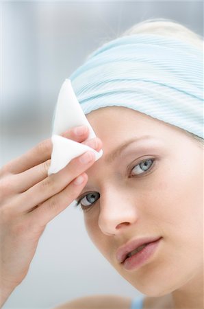 removes eye makeup - Young Woman face using a cleansing cotton on her forehead, close-up (studio) Stock Photo - Premium Royalty-Free, Code: 6108-05855732