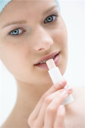 Young Woman face with make up, looking at the camera, using a lip balm, close-up (studio) Stock Photo - Premium Royalty-Free, Code: 6108-05855739
