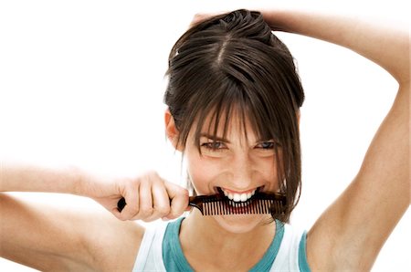 Portrait of a young woman holding a comb in her mouth Stock Photo - Premium Royalty-Free, Code: 6108-05855841