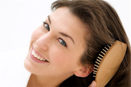 Portrait of a young woman brushing her hair Stock Photo - Premium Royalty-Free, Code: 6108-05855817