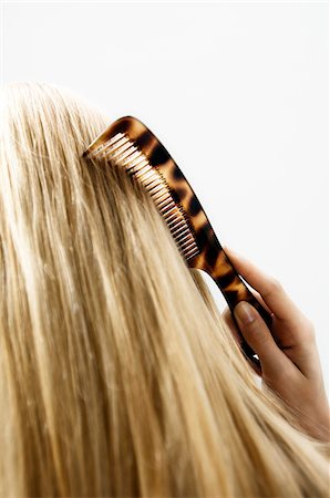 simsearch:6108-05855800,k - Portrait of a young woman combing her hair, view from the back, close up (studio) Foto de stock - Sin royalties Premium, Código: 6108-05855829