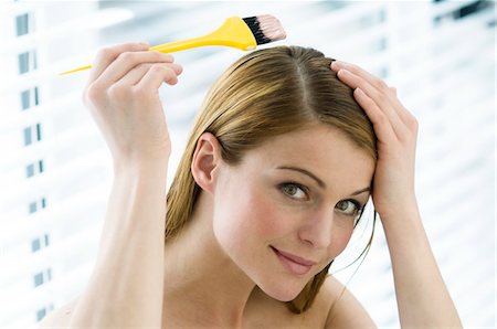 Portrait of a young woman dyeing her hair, little brush in her hand Stock Photo - Premium Royalty-Free, Code: 6108-05855830