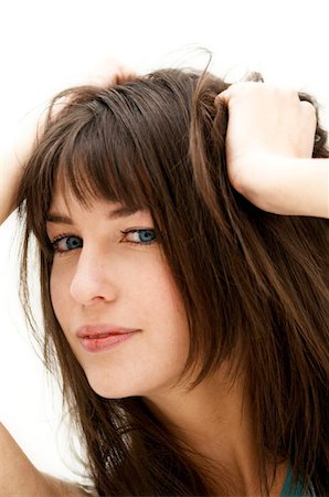 Portrait of a young woman, hands on her hair, close up (studio) Stock Photo - Premium Royalty-Free, Code: 6108-05855832