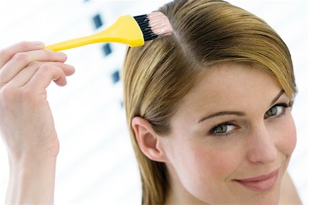 Portrait of a young woman dyeing her hair, little brush in her hand Fotografie stock - Premium Royalty-Free, Codice: 6108-05855836