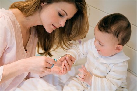 Young woman trimming her baby's fingernails Stock Photo - Premium Royalty-Free, Code: 6108-05855987