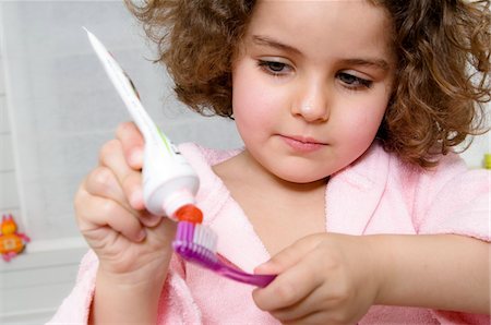 Little girl squeezing toothpaste onto toothbrush Stock Photo - Premium Royalty-Free, Code: 6108-05856083