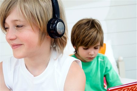 simsearch:6108-05856094,k - 2 boys at home, one wearing headphones, the other reading in background Stock Photo - Premium Royalty-Free, Code: 6108-05856094