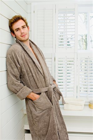 Young man in bathrobe, leaning against wall, looking at the camera Stock Photo - Premium Royalty-Free, Code: 6108-05856149