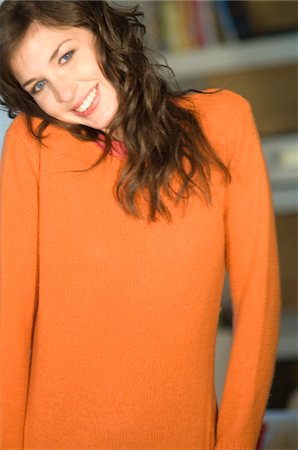 emotion - Young smiling woman with orange sweater, looking at the camera Stock Photo - Premium Royalty-Free, Code: 6108-05856486