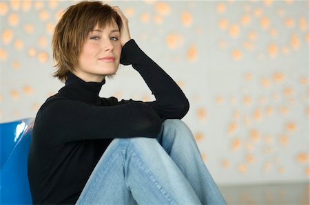 simsearch:6108-05856479,k - Young woman sitting on the floor, looking at the camera Stock Photo - Premium Royalty-Free, Code: 6108-05856416