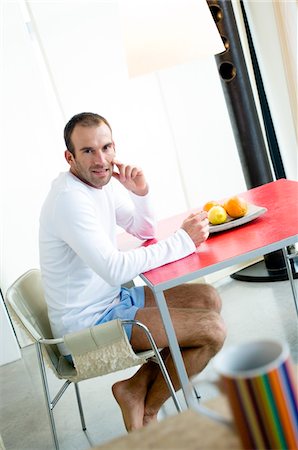 Man at breakfast table, looking at the camera, cup in foreground Stock Photo - Premium Royalty-Free, Code: 6108-05856583