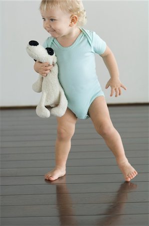 Little boy holding stuffed dog, standing on wooden floor Foto de stock - Sin royalties Premium, Código: 6108-05856647