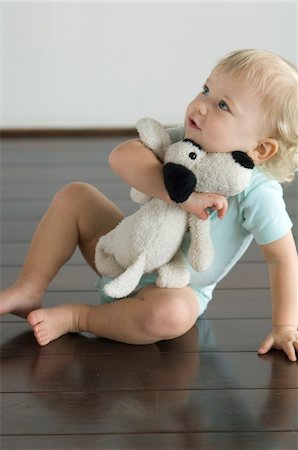 people with stuffed animals - Little boy sitting on the floor, holding stuffed dog Stock Photo - Premium Royalty-Free, Code: 6108-05856646