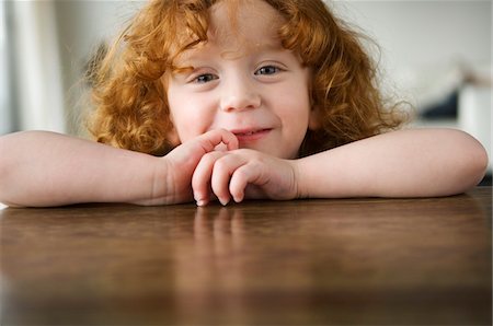 Little girl resting her arms on a coffee table, looking at the camera Foto de stock - Sin royalties Premium, Código: 6108-05856660