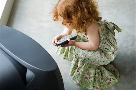 Little girl crouching in front of television, holding remote control, elevated view Foto de stock - Sin royalties Premium, Código: 6108-05856680