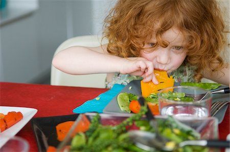 Little girl at lunch table, eating with hands Stock Photo - Premium Royalty-Free, Code: 6108-05856605