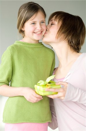 Woman holding present, kissing little girl on her cheek Stock Photo - Premium Royalty-Free, Code: 6108-05856606