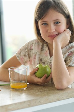 dietary supplements container - Portrait of a little girl eating an apple, looking at the camera Foto de stock - Sin royalties Premium, Código: 6108-05856617