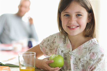 dietary supplements container - Portrait of a little girl eating an apple, man in the background Stock Photo - Premium Royalty-Free, Code: 6108-05856638