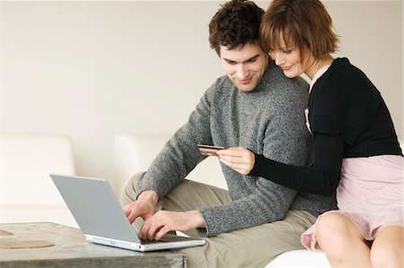 Man using laptop computer, woman holding credit card Stock Photo - Premium Royalty-Free, Code: 6108-05856703
