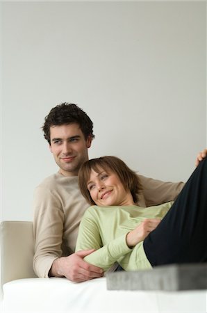 simsearch:6108-05856799,k - Couple souriant, couché sur un sofa Photographie de stock - Premium Libres de Droits, Code: 6108-05856718