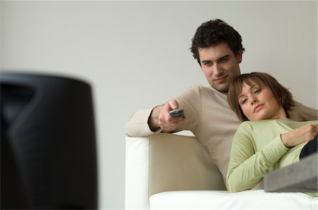Couple lying on a sofa, watching TV Stock Photo - Premium Royalty-Free, Code: 6108-05856733